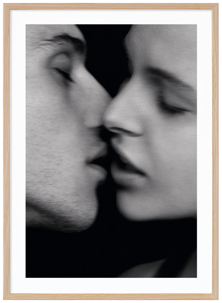 Black and white photograph of a woman and a man just about to kiss. Oak frame. 