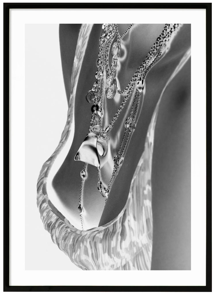 Black and white photograph of female breasts with exclusive necklaces. Black frame. 