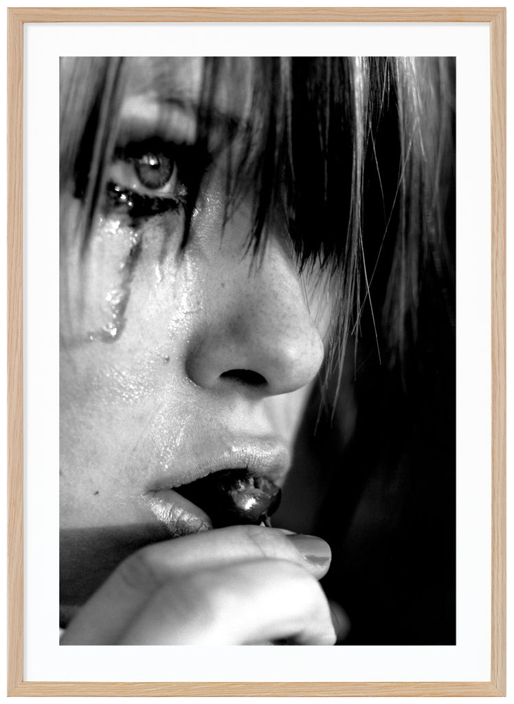 Black and white posters. Close-up of person crying and eating cherries. Oak frame. 