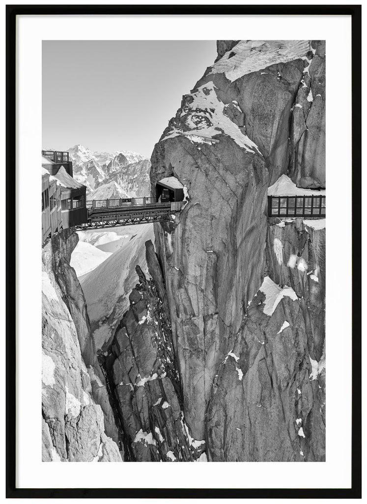 The dramatic view of the bridge atop the Aiguille du Midi in the French Alps. Black frame. 