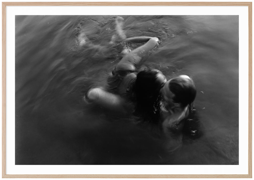 Analogous photograph of a woman and man hugging in water. Oak frame. 