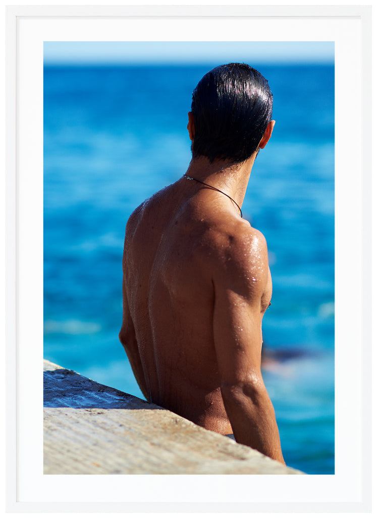 Poster of a man's naked backboard by the sea. Portrait format. White frame. 