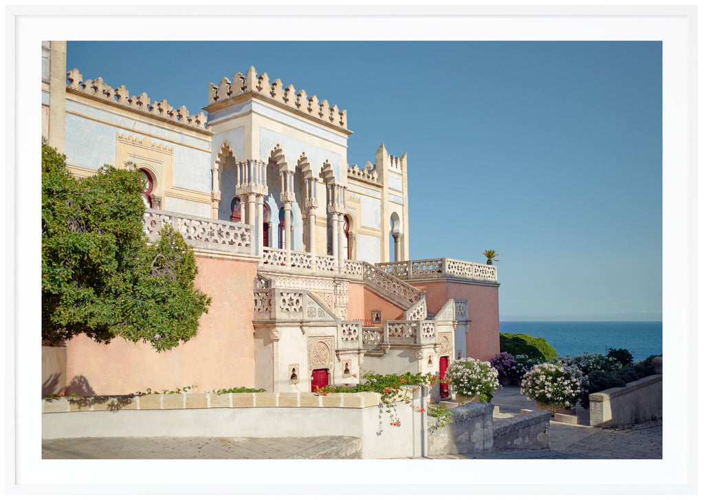Color photography of an Italian palace that goes in pastel tones with clear Moorish influences in the architecture.  White frame. 