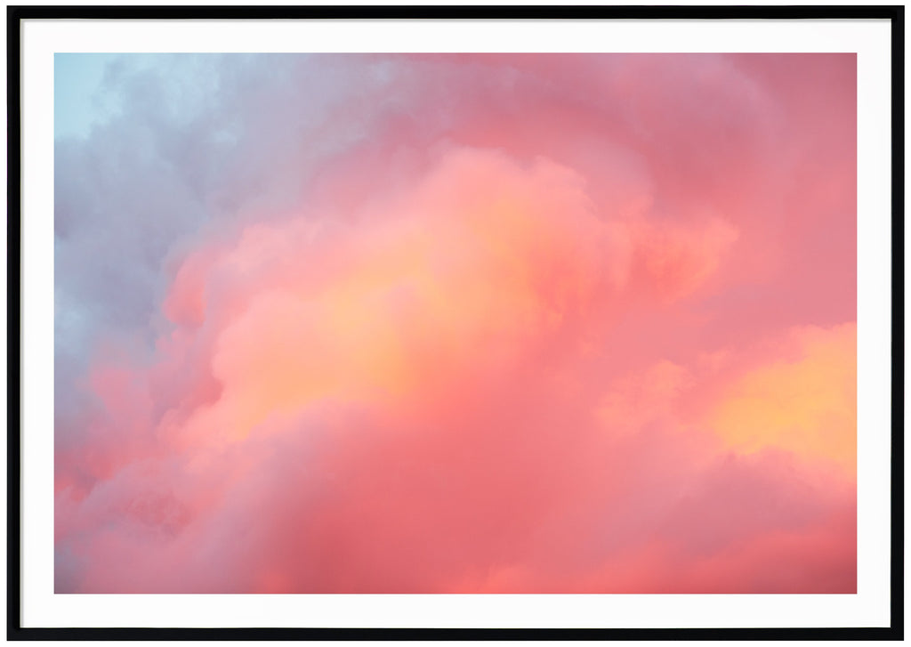 Color photograph of clouds in blue, pink, purple, orange. Horizontal format.  Black frame.