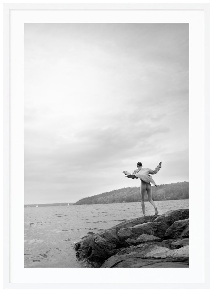 Black and white photograph of a woman on rocks in the archipelago. White frame. 