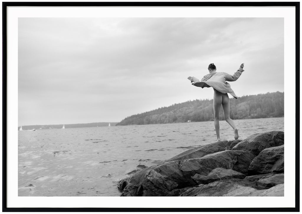 Black and white photograph of a woman on rocks in the archipelago.  Black frame. 