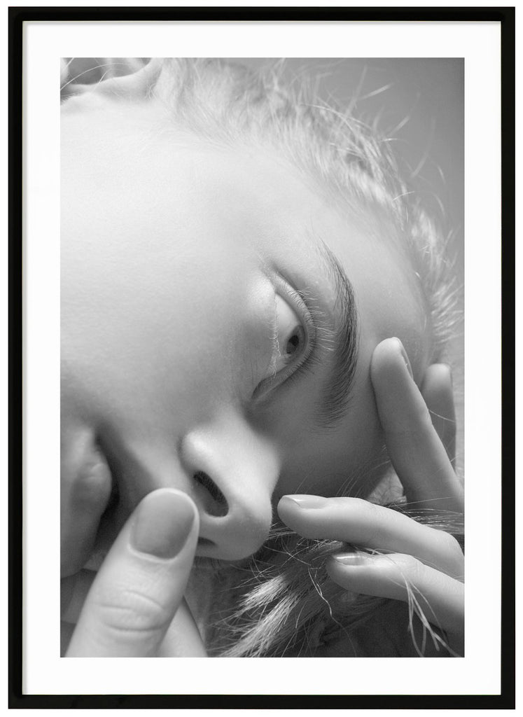 Black and white photo art depicting a woman's face seen from a different photographic perspective. Black frame.