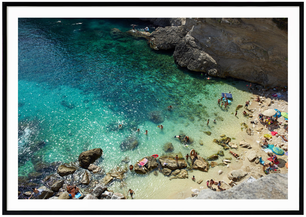 Color photography of a beach and cliffs in southern Italy. Black frame.