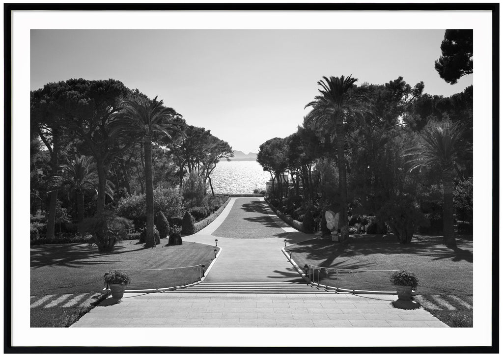 Black and white photography with a view of an incredible backyard with the water glistening with the sun.  Black frame. 