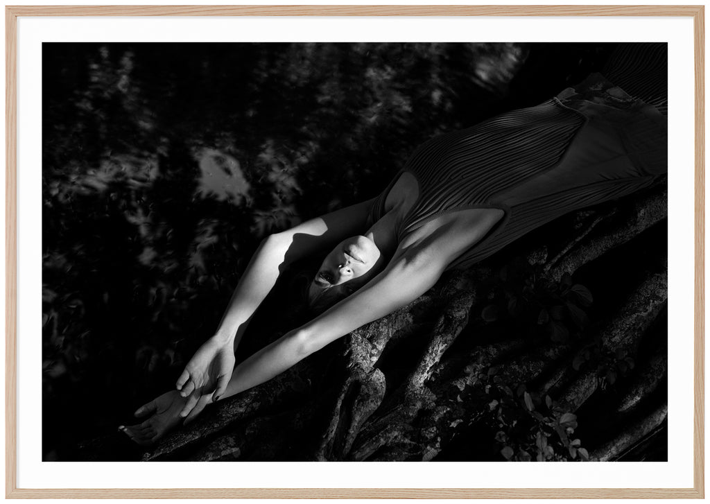 Black and white photograph of a woman lying on a mangrove tree near the water. Oak frame. 