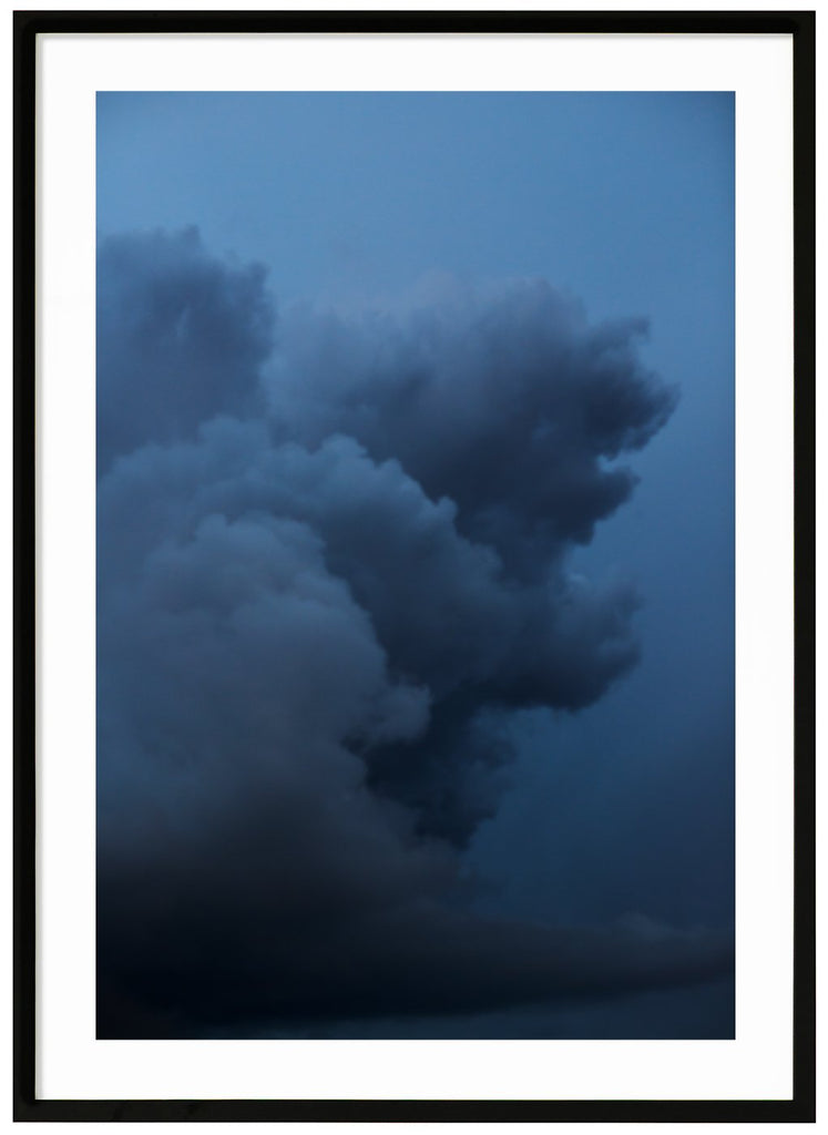 Photograph of dark clouds in the colors of dark blue. Black frame. 