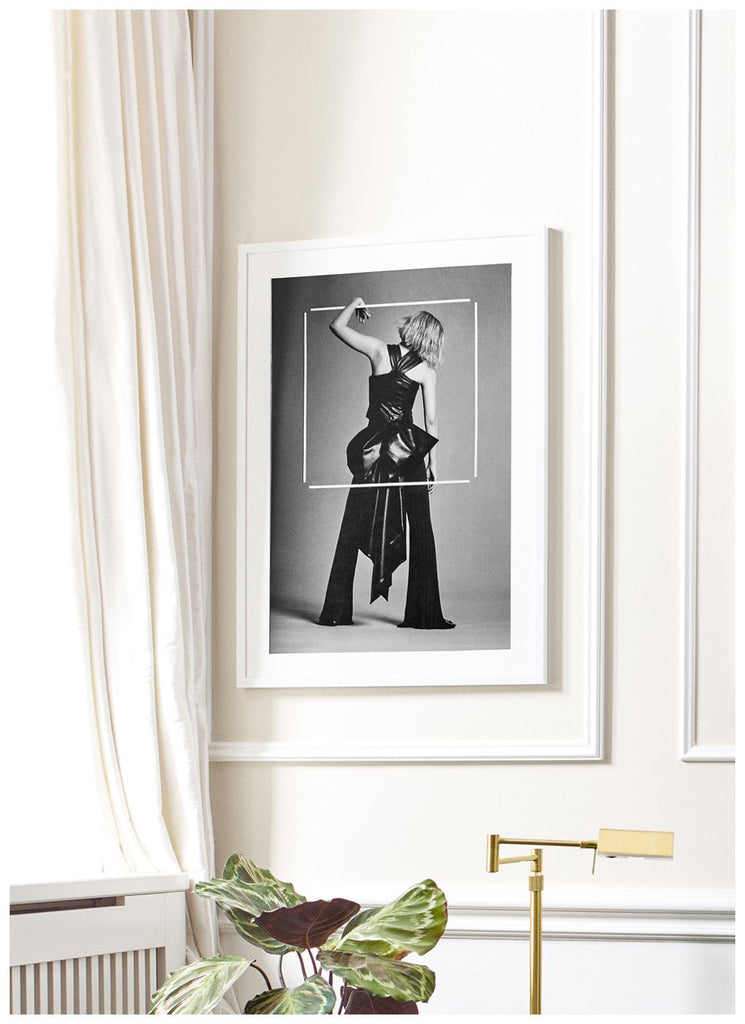 Also Magic Poster - Black and white photo art framed hanging in a living room environment. Fashion photography, in a black frame depicting woman in studio, seeming to hang on a white frame floating in the air. White frame. 