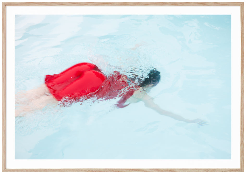 Poster of woman in red dress diving into light blue pool. Oak frame. 
