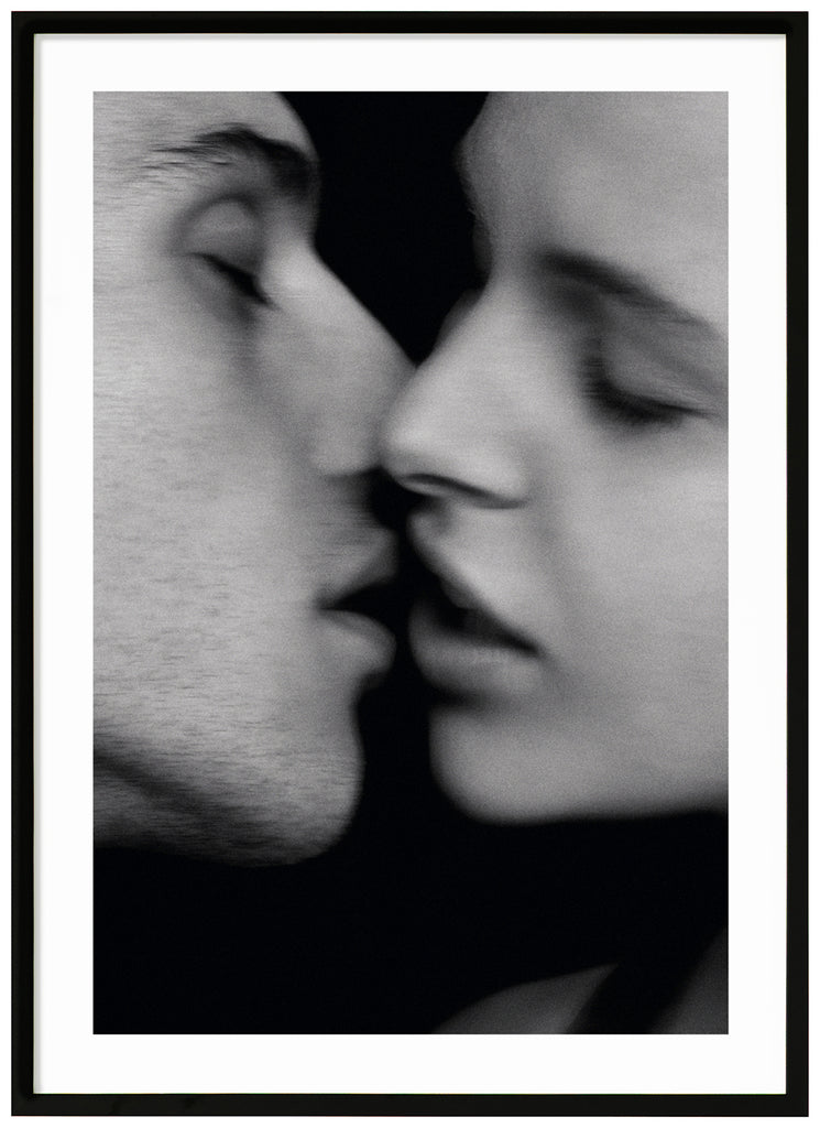 Black and white photograph of a woman and a man just about to kiss. Black frame. 