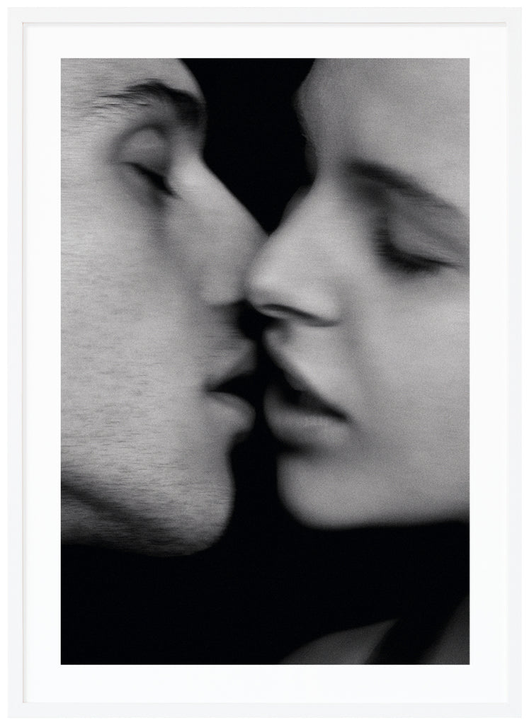 Black and white photograph of a woman and a man just about to kiss. White frame.
