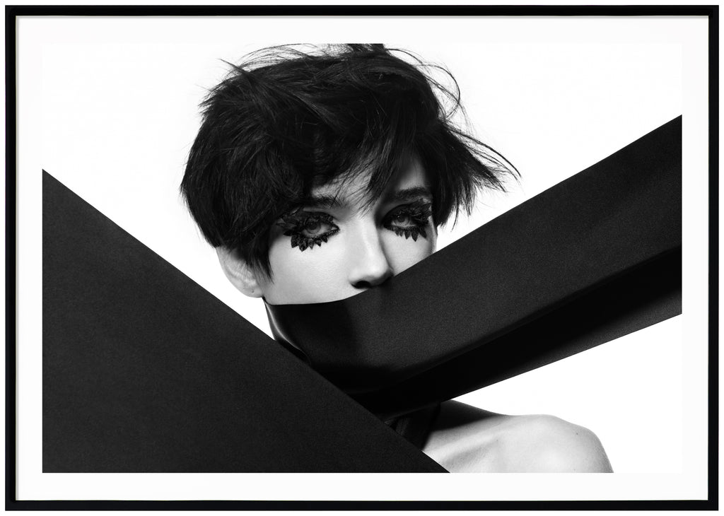Graphic black and white poster of make-up woman with cloth over her mouth. Black frame. 