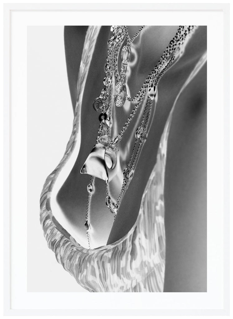 Black and white photograph of female breasts with exclusive necklaces. White frame. 