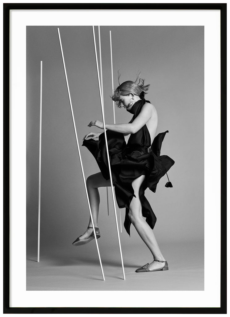 Black and white poster of woman wearing black seen from the side in photo studio. Black frame. 