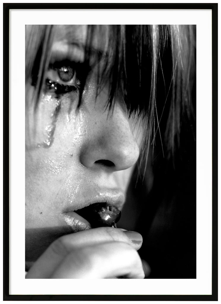 Black and white posters. Close-up of person crying and eating cherries. Black frame. 