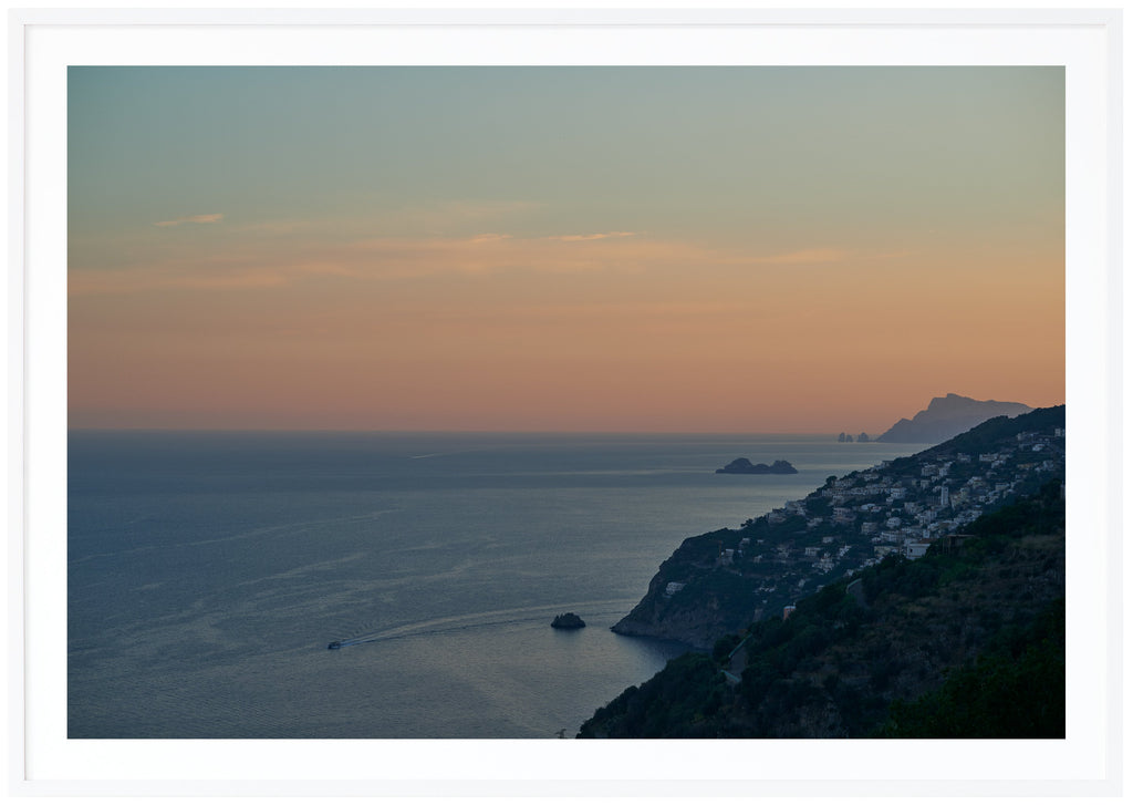 View over water, mountains and boats. During sunset.  White frame. 