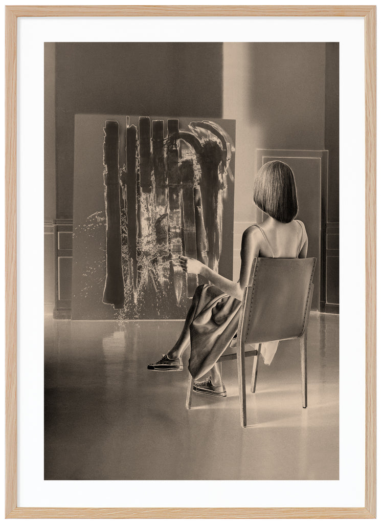 Monochrome warm-toned poster of seated woman looking at a work of art. Oak frame. 