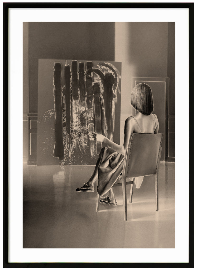 Monochrome warm-toned poster of seated woman looking at a work of art. Black frame. 