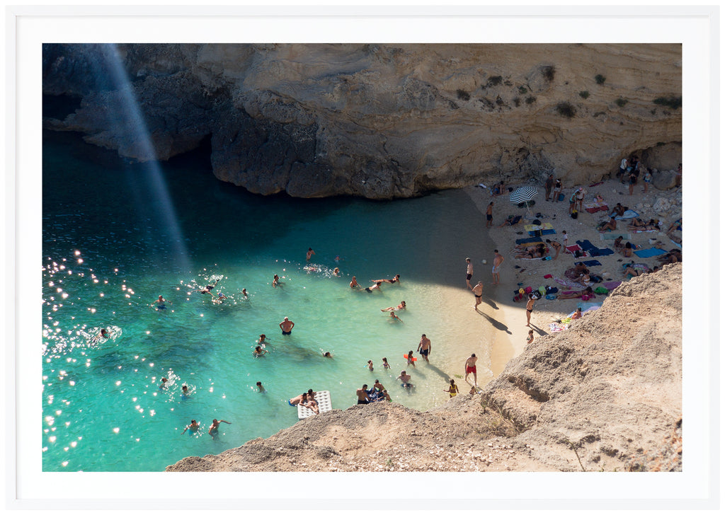 Posts of bathing place by rocks. Sparkling water. Landscape format. White frame. 