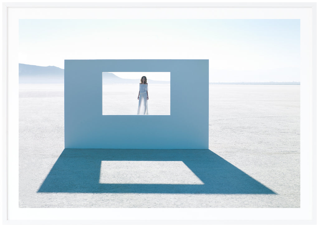 Poster of a woman standing behind a wall. White frame. 