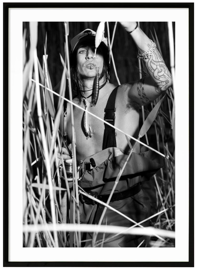 Black and white poster by Andreas Tyrone Dregen fishing among reeds. Black frame.