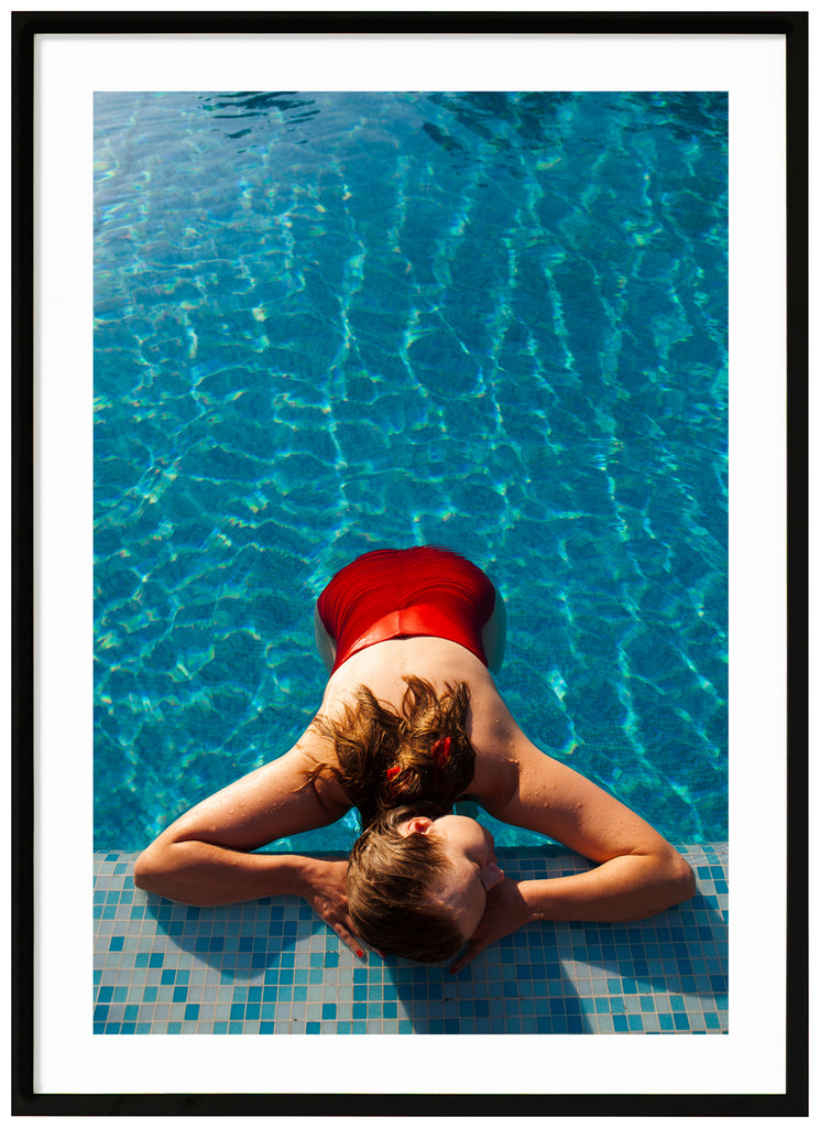 Poster of woman in red swimsuit lying on poolside. Black frame. 