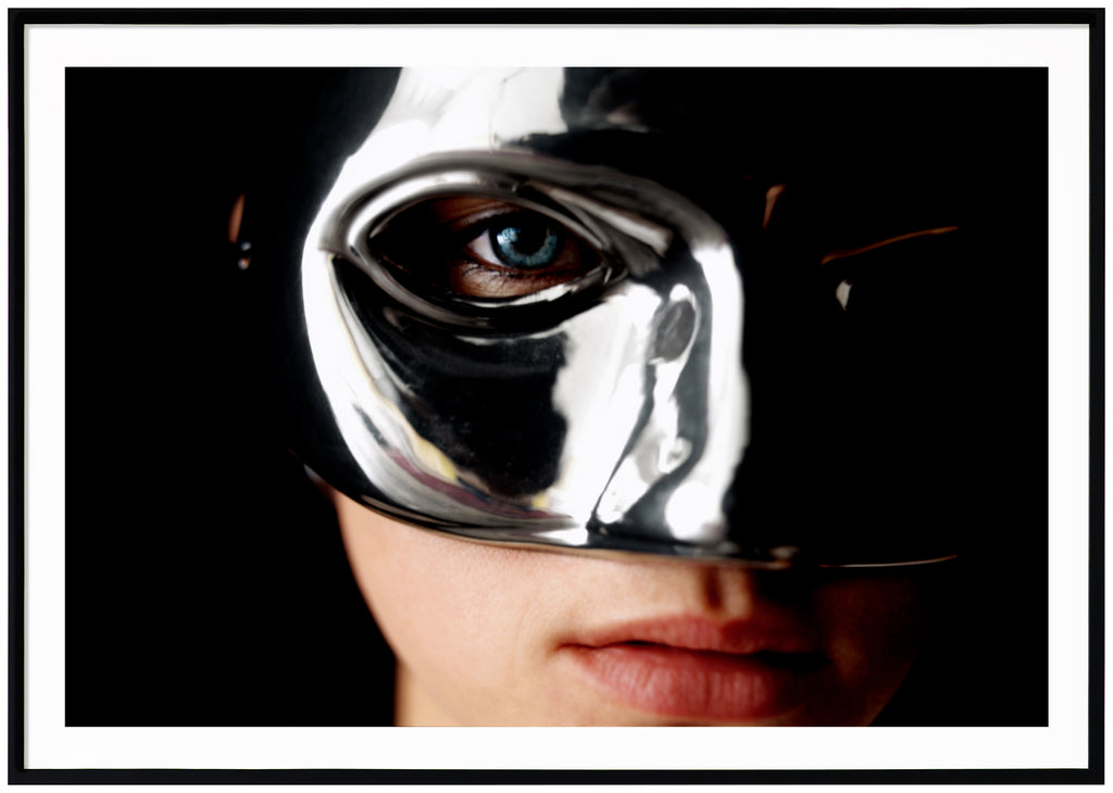 Poster of a woman's face wearing a silvery mask. Black frame. 