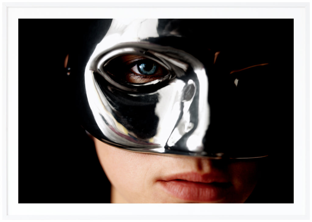 Poster of a woman's face wearing a silvery mask. White frame.