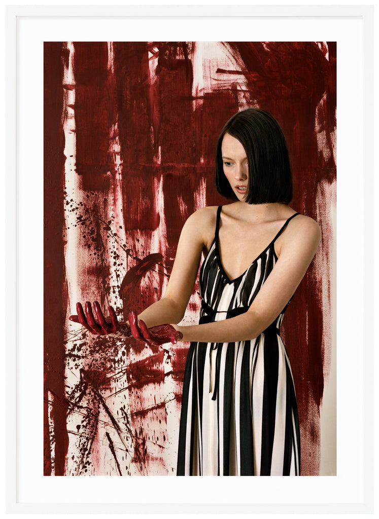 Woman standing in front of an abstract work of art.  White frame. 
