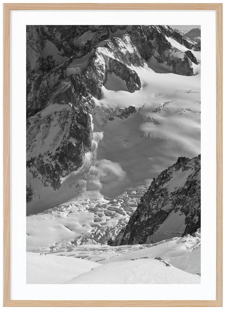 black and white items of sun-drenched snow cover over the mountains of the Alps. Oak frame. 