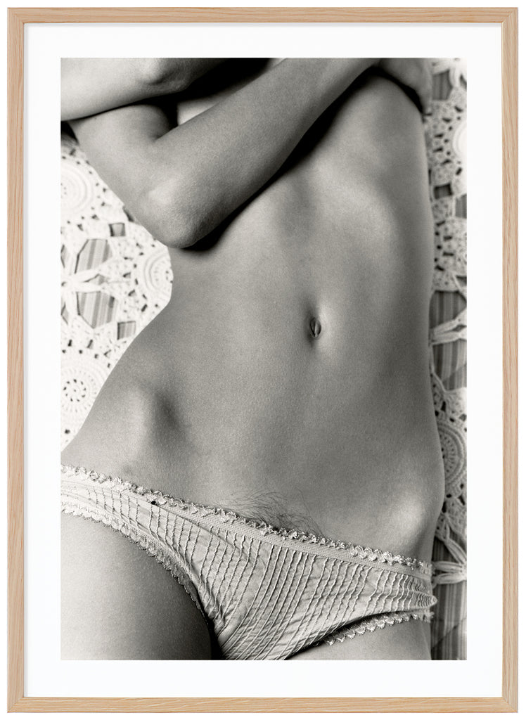 Analogous photograph of a woman lying on her back in panties and embracing her breasts.  Oak frame.