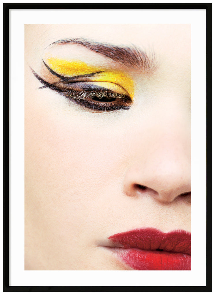 Photograph of close-up of woman with make-up in yellow, red and black. Black frame.