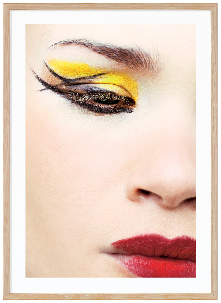 photograph of close-up of woman with make-up in yellow, red and black. Oak frame. 