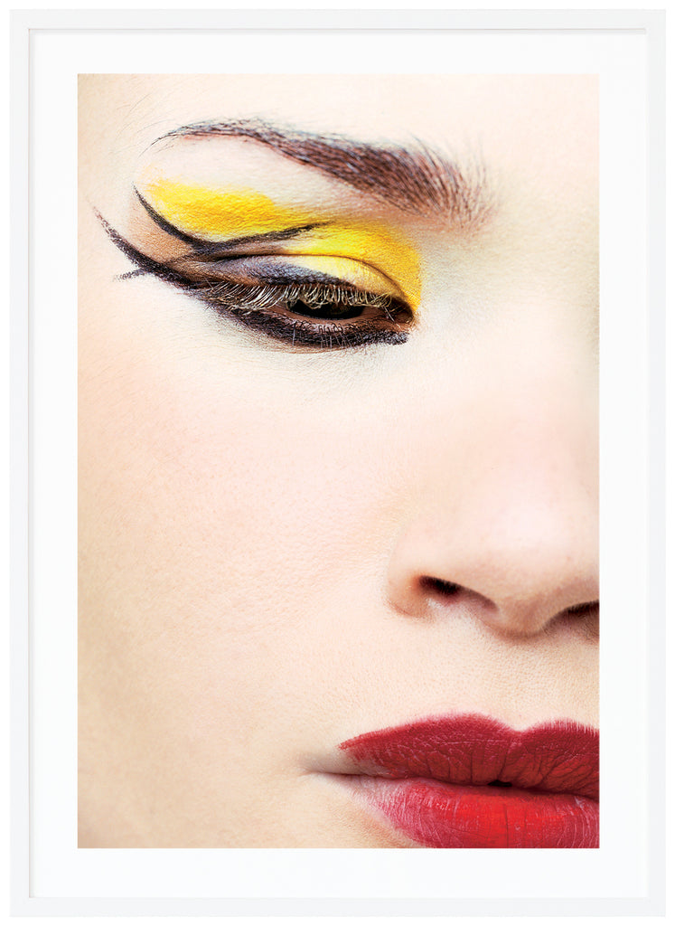 photograph of close-up of woman with make-up in yellow, red and black. White frame.