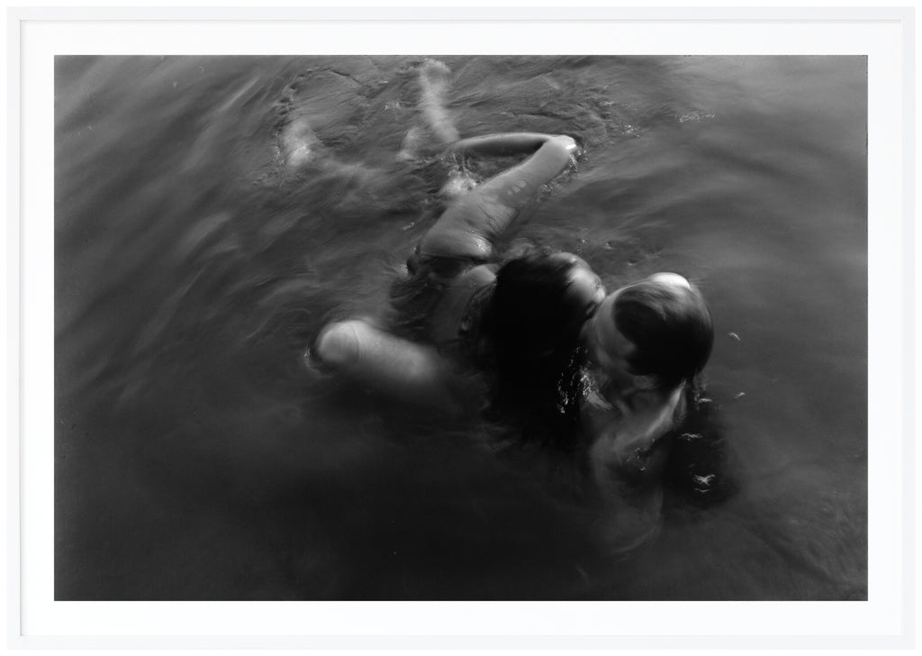 Analogous photograph of a woman and man hugging in water.  White frame. 