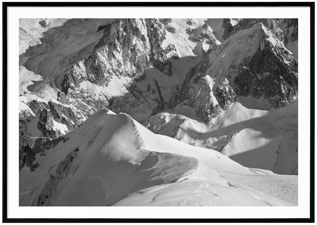 Black and white photograph of snow-capped Alps. Black frame. 