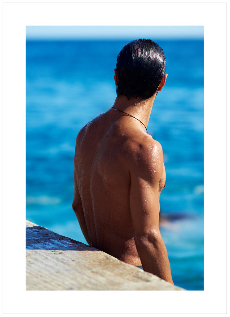 Poster of a man's naked backboard by the sea. Portrait format.
