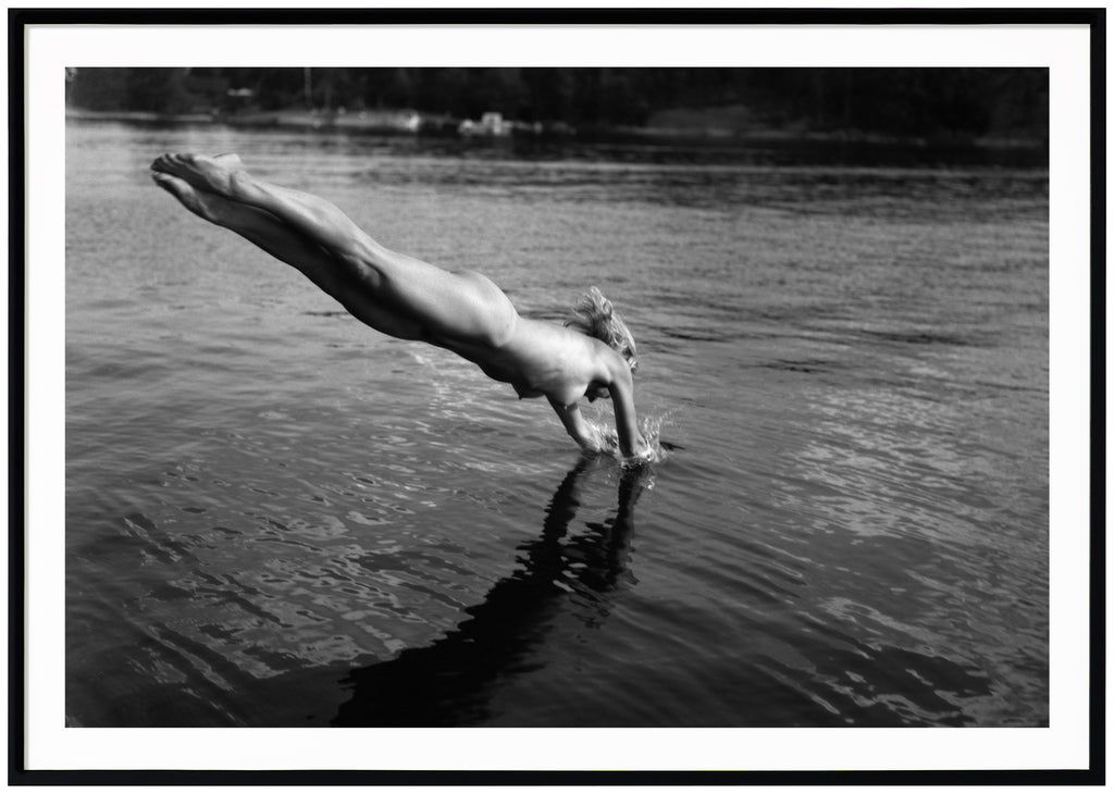 Analogous photograph in black and white, of a naked woman diving into the water. Black frame. 