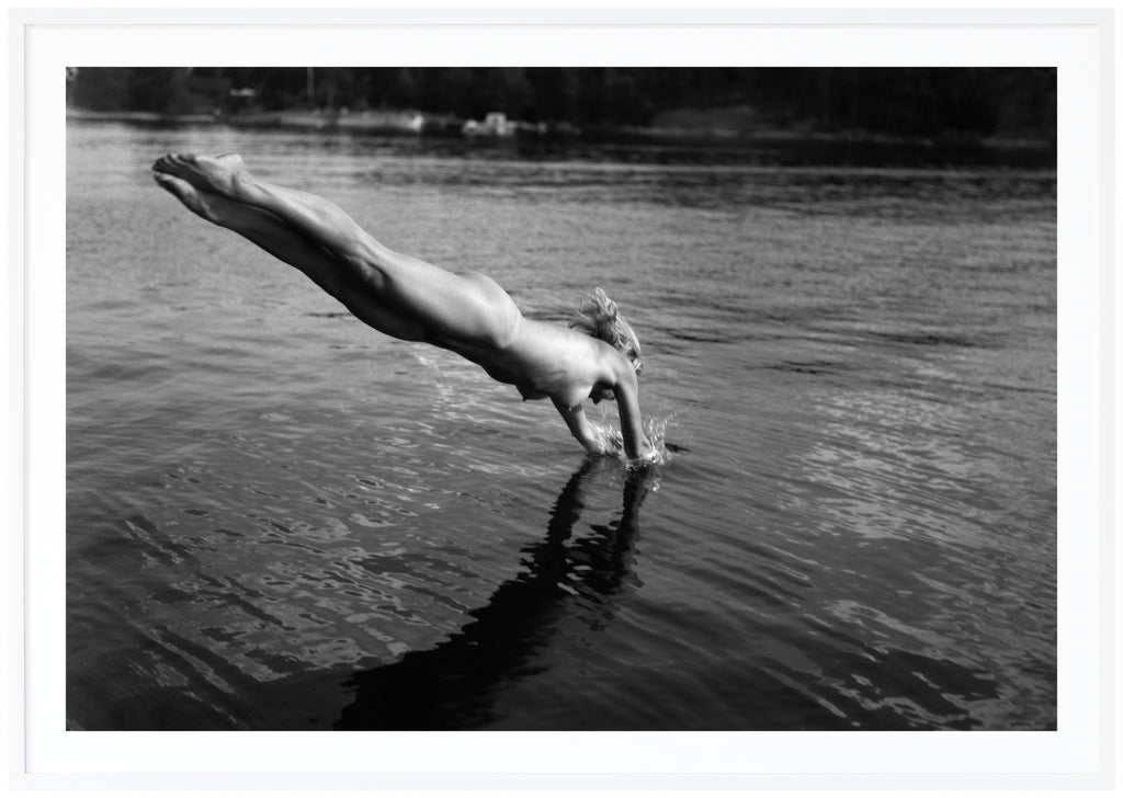 Analogous photograph in black and white, of a naked woman diving into the water. White frame. 