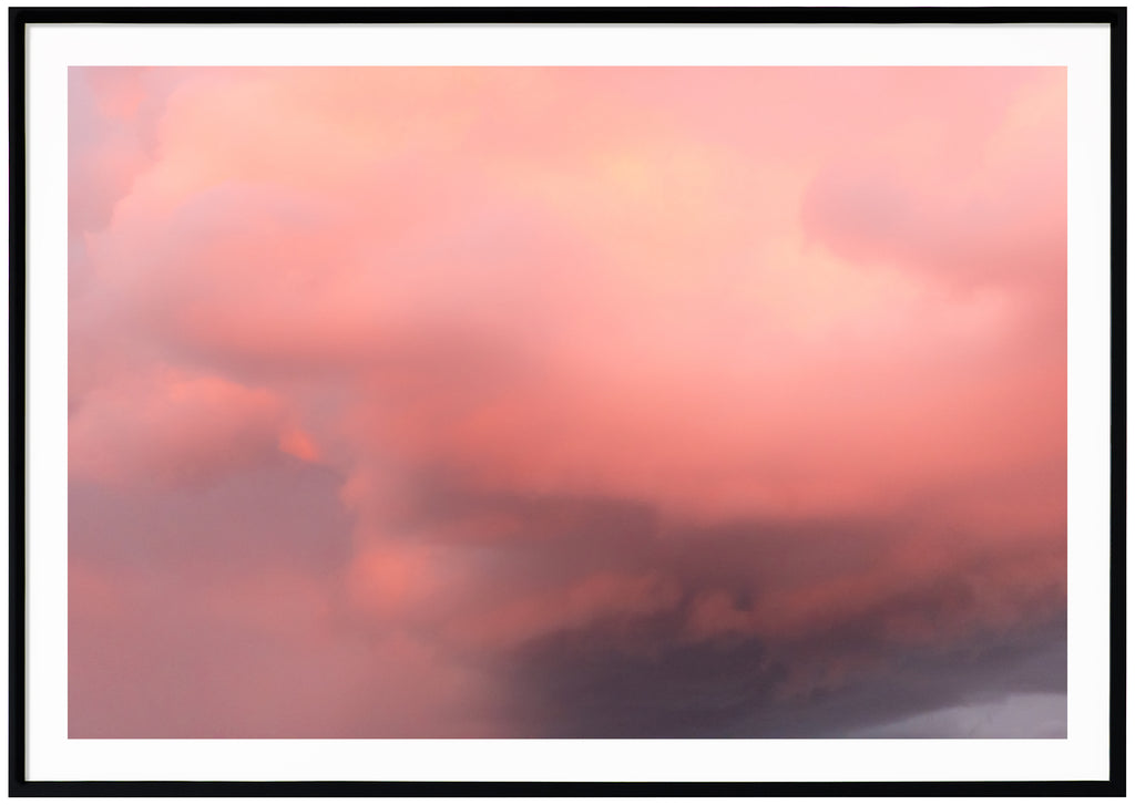 Color photography of clouds in the tones of pink, purple and yellow. Black frame. 