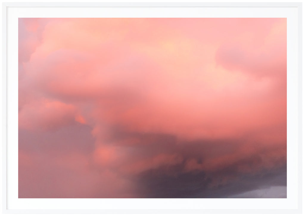 Color photography of clouds in the tones of pink, purple and yellow. White frame. 