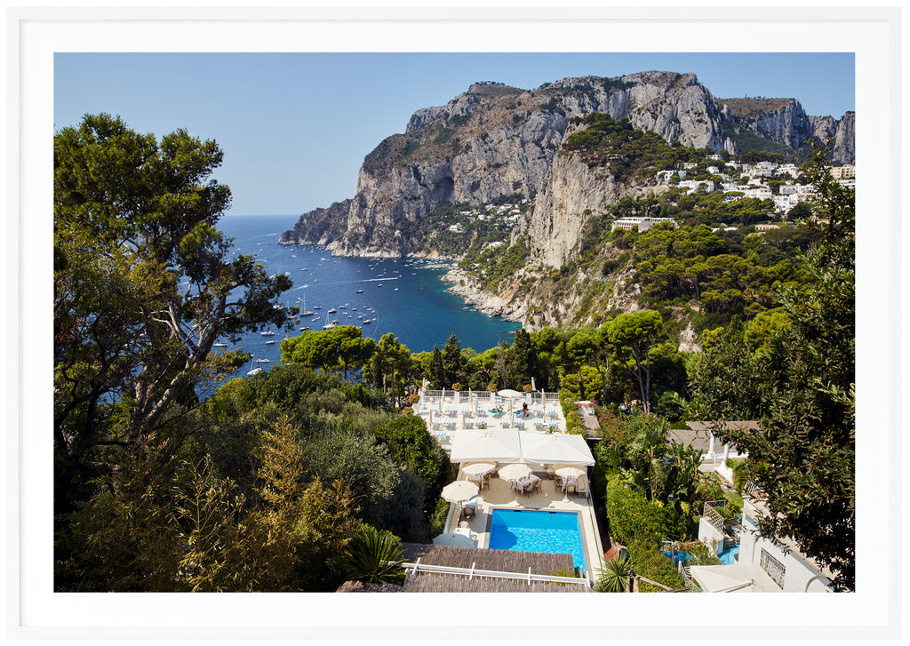 Horizontal photography in color view of a swinging pool and mountains on the island of Capri in Italy.  White frame. 