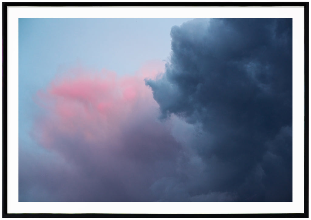 Photograph of dark blue, pink, purple clouds. Horizontal format.  Black frame. 
