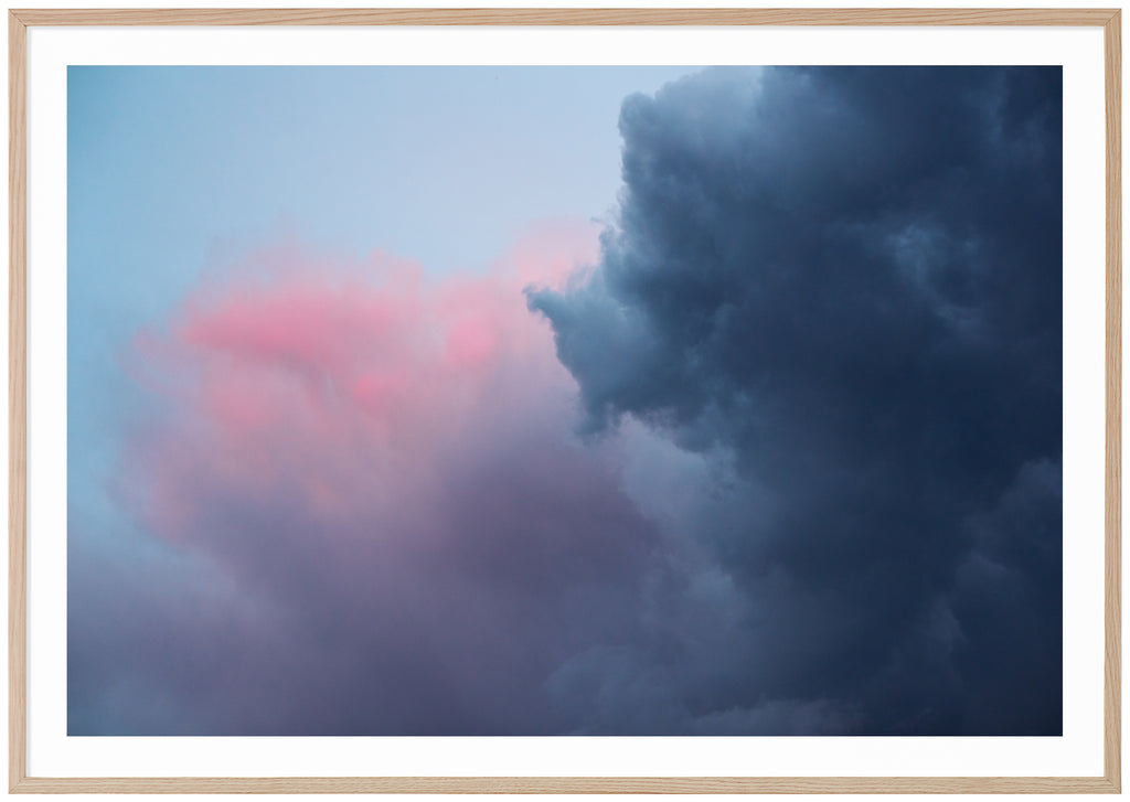 Photograph of dark blue, pink, purple clouds. Horizontal format.  Oak frame. 