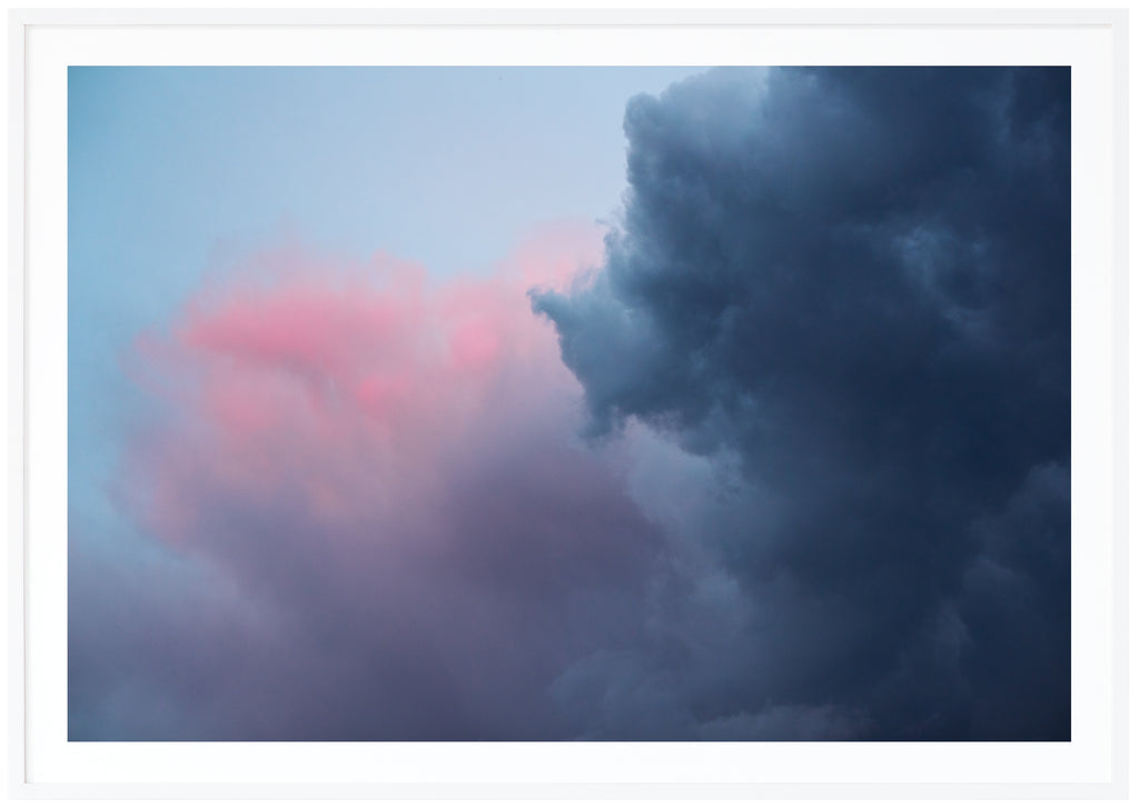 Photograph of dark blue, pink, purple clouds. Horizontal format. White frame. 