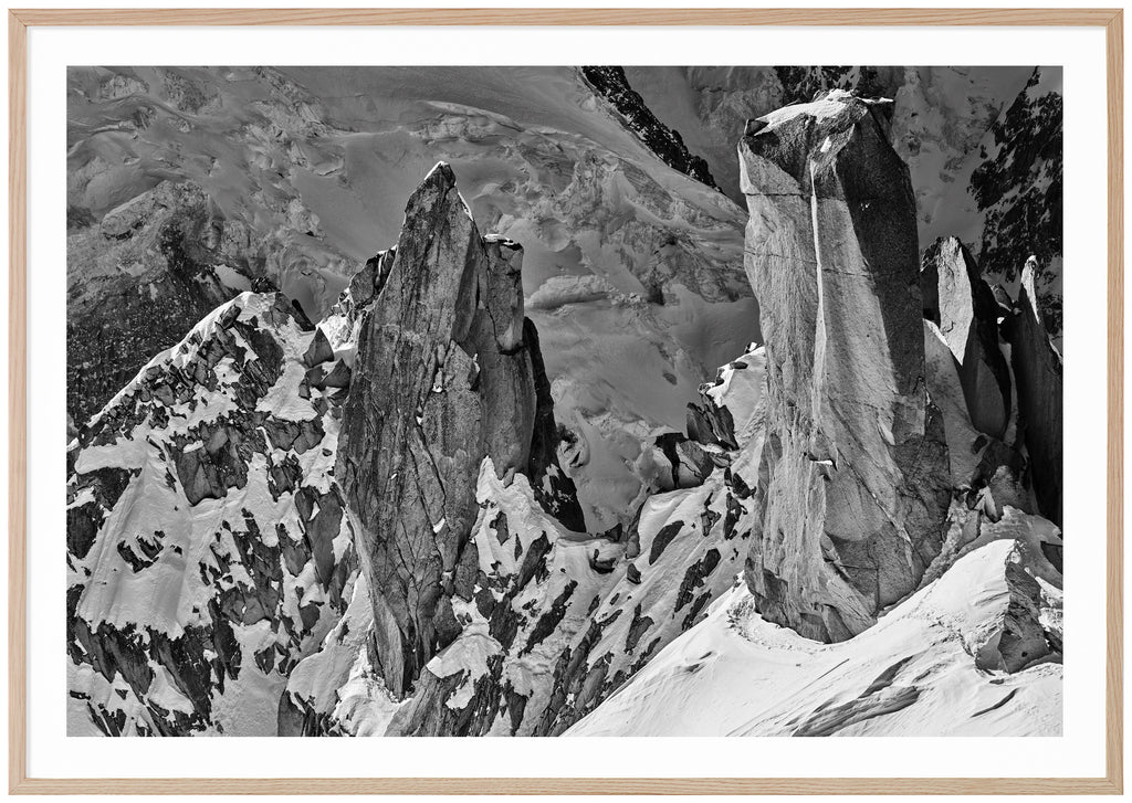 Black and white photograph of steep cliffs partly covered by snow.  Oak frame. 